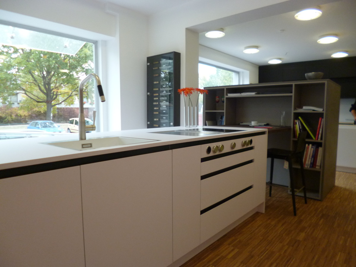 Modernes Küchen- und Arbeitszimmer mit Arbeitsplatte, Schränken, Fenster und Bücherregal.